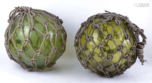 A pair of dumpy green glass fishing floats, each in rope surround, approximate height 67cm