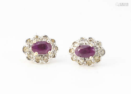 A pair of ruby and diamond oval cluster earrings, the oval mixed cut central claw set rubies