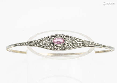 A Belle Epoque costume arm bangle, set with an oval pink paste stone, within a white metal setting