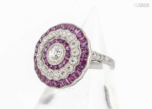 A ruby and diamond target ring, centred with old cut diamond in platinum surrounded by a bezel of