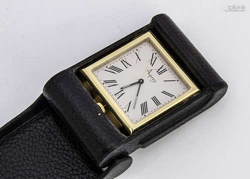 A c1980s travel clock from Asprey, the gilt square quartz time piece in black leather folding case