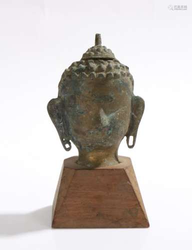 Tibetan cast metal Buddha head, mounted on a tapering wooden base, 17cm high
