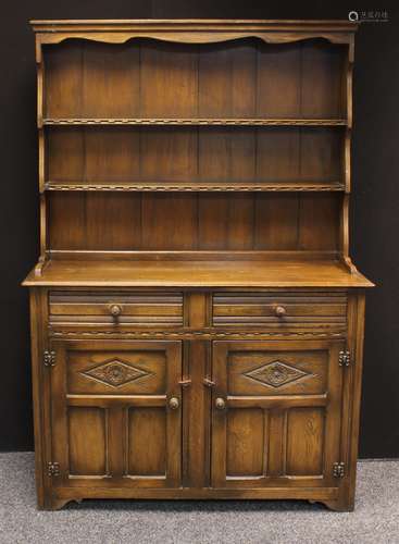 A 20th century oak dresser, outswept cornice above plate racks, the slightly projecting base with