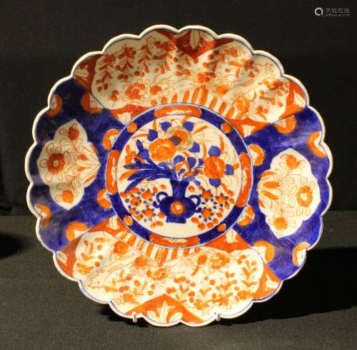 A Japanese Imari shaped circular charger, the central field painted with a vase of flowers, trails