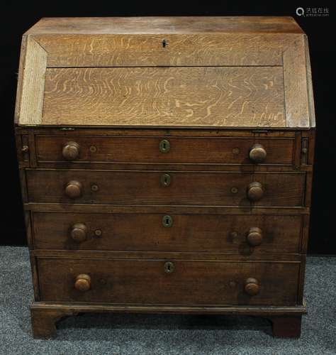 A George III oak bureau, fall front enclosing an arrangement of pigeonholes and small drawers, above