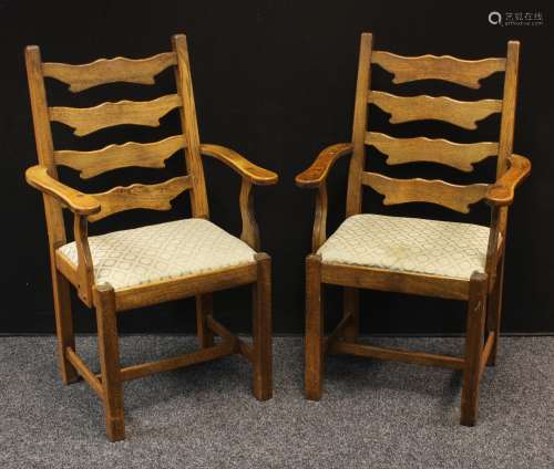 A pair of 20th century oak open armchair/carvers. shaped ladder-backs, slightly outswept arms,