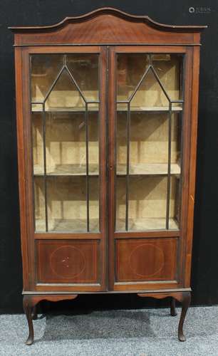 An Edwardian mahogany display cabinet, shaped cresting above a pair of astragal glazed doors