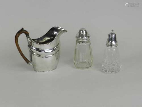 A silver plated jug and two silver mounted glass sugar casters