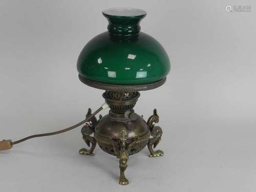 An Edwardian brass oil lamp, the globular reservoir raised on griffin feet, with green glass