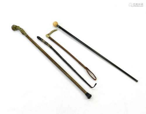 A group of three walking canes including one with an ivory cue ball top, and a riding crop with horn