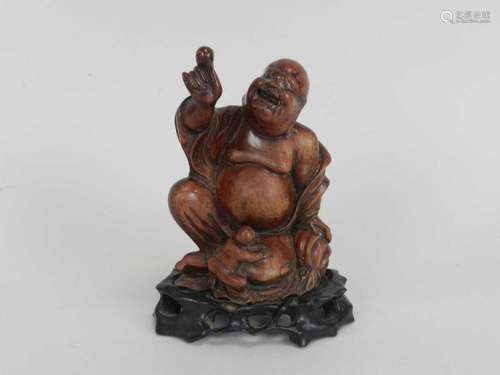 A Chinese carved hardwood figure of a laughing Buddha, modelled seated and accompanied by a boy,