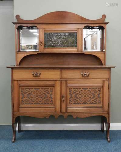 A late 19th century arts and crafts influence oak mirror-back sideboard, the scroll cresting above