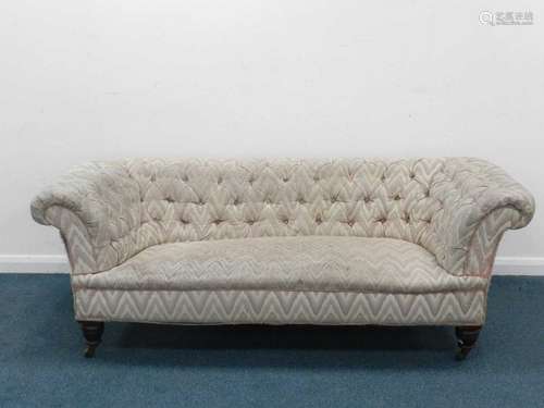 An upholstered Chesterfield sofa, of typical form with button back, raised on mahogany supports with