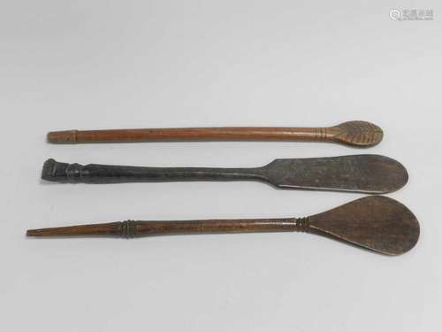 Three Oceanic tribal carved wood ceremonial objects, each of paddle form with turned handles,