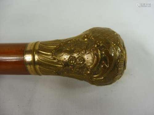 *Canne en bois vernis, pommeau en métal doré à décor Rocaille. Vers 1900 (Long. : 90 cm) (usures à la dorure)