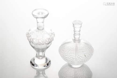 LALIQUE France. Lot de deux flacons en verre moulé pressé en partie dépoli : l'un sur piédouche à décor d'une frise de roses (H : 14,5 cm), le second à décor d'empreintes de feuillages (H : 12,5 cm). Signés au revers