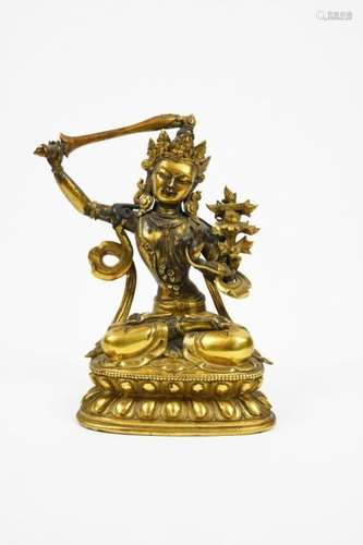 Sujet en bronze doré représentant le bodhisattva Manjusri, assis en padmasana sur un double lotus, paré de bijoux et couronné d'une tiare, la main droite levée, brandissant l'épée, la gauche en vitarka mudra, geste de l'argumentation, la main tenant une tige de lotus dont la fleur à hauteur de l'épaule gauche, porte le livre. Base scellée, incisée d'un visvavajra.  Tibet, XVIIIe siècle. H. 16 cm. Provenance : Collection du Baron de M., administrateur des Douanes en Chine dans les années 1920. Puis par descendance.Expert : Cabinet Ansas et Papillon Pour participer aux enchères du lot 77 une caution sera demandée.To bid on this lot 77, a deposit will be required.Pas d'enchères en LIVE / No bid in Live