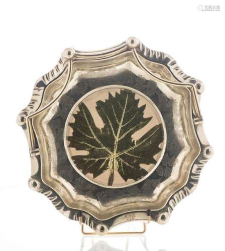 Corbeille en métal argenté, à anse mobile, les bords chantournés, décor gravé de feuilles de gingko biloba et centrée d'une feuille d'érable dorée sous verre, sur quatre pieds boule. Chiffrée et datée 1895 (H : 7 cm, diam : 28,5 cm)