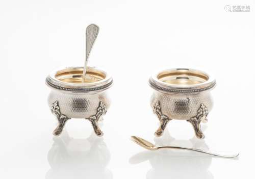 Paire de salières en argent à décor d'une frise de perles, chiffrée 'WG' sur fond guilloché, sur quatre pieds en feuilles d'acanthe, avec leurs deux pelles à sel au même chiffre (Poids total sans les doublures : 106 g) (une doublure de verreaccidentée)