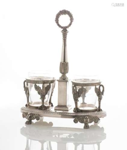 Huilier-vinaigrier en argent, poinçon Vieillard (1819-1838), à décor de cygnes adossés, d'une colonne à base carrée et couronne de cornes d'abondance, la base ovale ornée d'une frise de feuilles d'eau, sur des pieds griffes. Travail de style Empire. (Poids hors montures : 1150 g) (petite fente) ; on y joint deux verres gravés (sans les flacons d'origine)