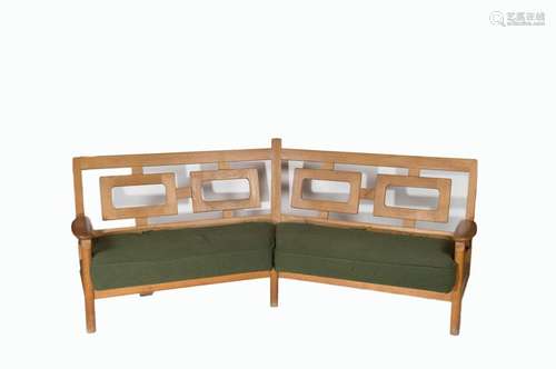 Robert GUILLERME (1913-1990) et Jacques CHAMBRON (1914-2010) - Edition VOTRE MAISON. Grande banquette d'angle en chêne clair, dossier ajouré à motif de rectangles, couverture de tissu vert (94 x 242 x 84 cm) (usure et accidents au tissu)