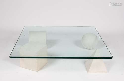 D'après Lella et Massimo VIGNELLI (1934-2016 et 1931-2014). Table basse, d'après le modèle Metafora, piétement composé de quatre formes en pierre calcaire supportant un plateau en verre(24 x 100 x 100 cm)Les formes géométriques de cette table créée en 1979 font référence à la Terre (la sphère), à l'Egypte (la pyramide), la Mecque (le cube) et l'Empire Romain (le cylindre renversé).