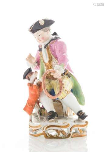 Groupe en porcelaine émaillée polychrome et or figurant un homme assis avec un chien au cerceau, sur une terrasse Rocaille ajourée, marques au revers. Allemagne, fin XIXème siècle. (H : 12,5 cm)