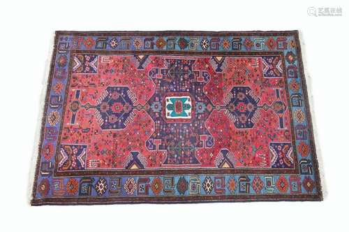 Tapis en laine, à décor d'un polygone central sur fond rouge orné d'animaux stylisés, bordure à décor de motifs géométriques sur fond bleu clair (186 x 132 cm)