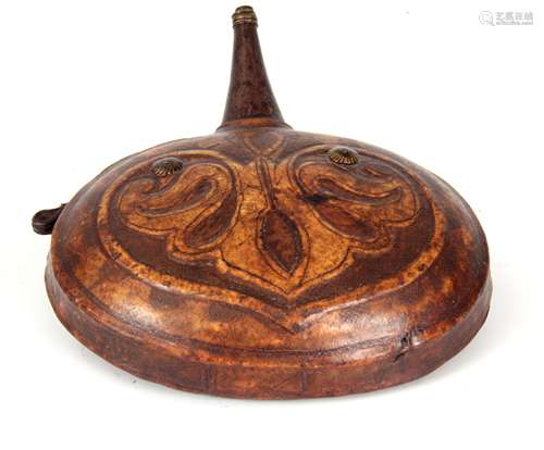 A 19TH CENTURY INDIAN TOOLED LEATHER POWDER FLASK with ironwork funnel and leaf designed circular