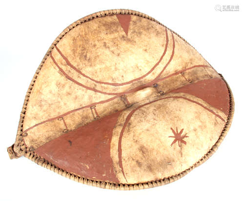 AN AFRICAN HIDE CHIEFTAIN'S SHIELD with bound stitched border and dark red painted decoration 74cm