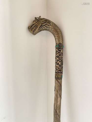 东南亚，约1900年。剑杖的剑柄上有马卡拉的头，其尾巴和腿缠绕在剑杆上。一条绿松石镶嵌带(缺11条)装饰着轴与剑杆之间的过渡。银和绿松石。刀片长度：54厘米。总长度：95厘米。