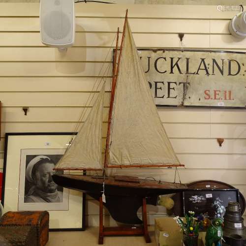A 19th century black lacquered wooden-hulled model pond yacht, with sails and rigging, hull