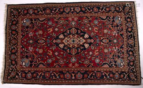 Persian red ground rug with central blue medallion and foliate border, 204cm x 125cm