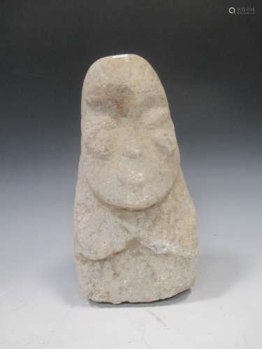 A Chinese carved stone head of a bearded man, of stylised form, perhaps Neolithic, 29cm high
