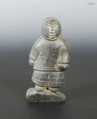 An Inuit carved greenstone figure of a hunter, circa 1960-70, standing in skins, on an angled