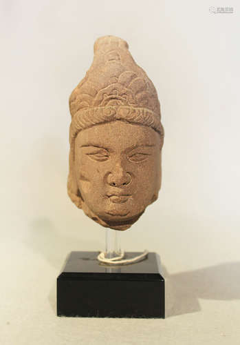 A red sandstone head of a Bodhisattva, possibly Tang Dynasty, with full face, the hair upswept to