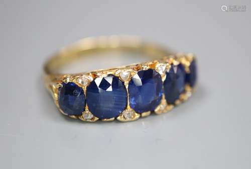 A George V 18ct gold and graduated five stone sapphire set half hoop ring, with diamond chip