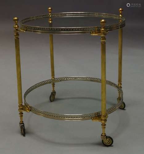 A silvered metal and brass two tier trolley, c.1960, the circular glass top with pierced gallery, on