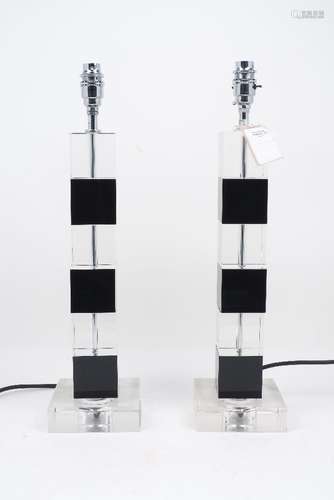 A pair of glass table lamps, each of rising square column form, with recurrent black and clear