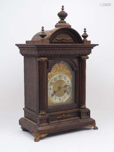 An Edwardian oak bracket clock, of architectural form with a semi-circular tympanum flanked and