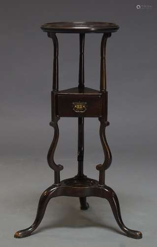 A George III style mahogany wig stand, early 20th Century, the circular top on scrolling supports to