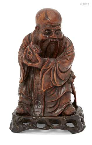 A Chinese hardwood figure of Shou Lao, 19th century, carved holding a peach and standing atop a