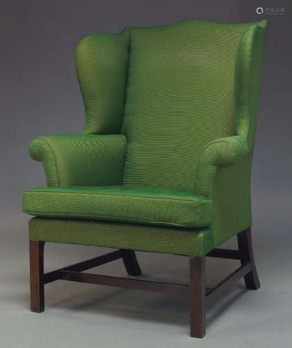 A George III wingback armchair with serpentine wings and loose seat cushion, upholstered in green