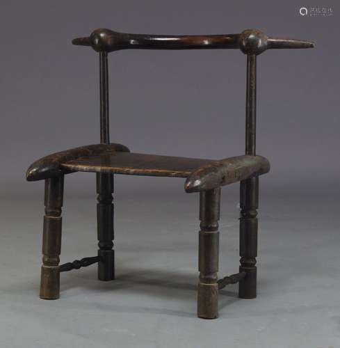 An Ivory Coast carved African chair, 20th Century, with curved back rail on tapered supports to