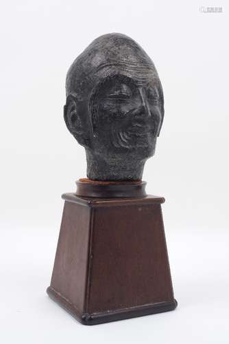 An Indian black schist carving of the head of the emaciated Shakyamuni Buddha, mounted on a tapering