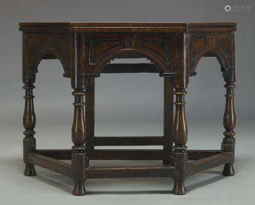 An oak credence table, early 20th Century, with folding octagonal top, above arcaded frieze on