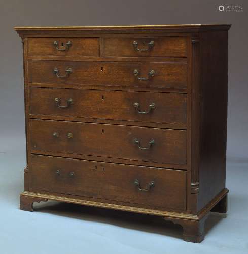 A George III oak chest of drawers, with two short over four long graduated drawers, flanked by