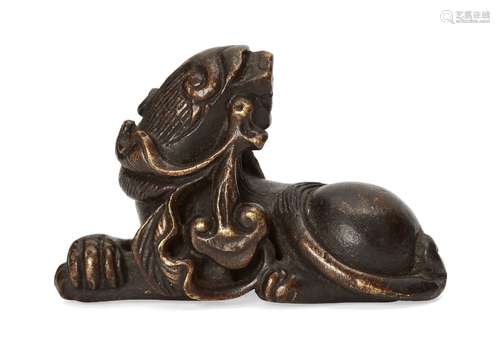 A Chinese bronze lion dog scroll weight, Ming dynasty, 17th century, modelled in recumbent pose