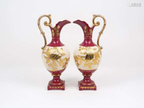 A pair of ceramic wine ewers of red and cream ground, with gilt decorative highlights of leafy