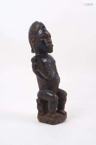 A Yoruba style African wood sculpture of a male figure, 20th century, with ovoid head and carved